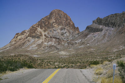 Road by mountains against clear sky