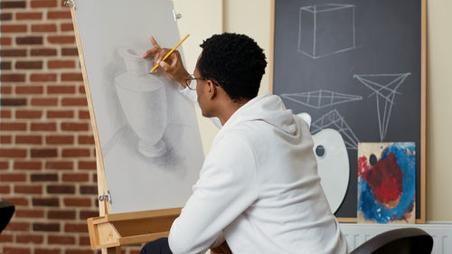 Man sketching on canvas in classroom