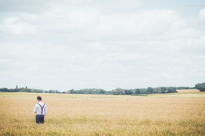 Rear view of man standing on field against sky