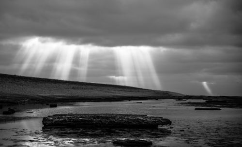 Sunlight streaming through storm clouds over sea