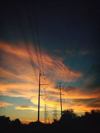 Low angle view of electricity pylon at sunset