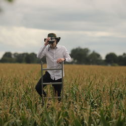 Side view of guy using polaroid camera while standing on field