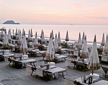 Panoramic view of chairs on beach against sky during sunset