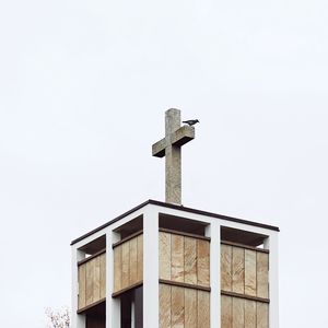 Low angle view of birdhouse against building against clear sky