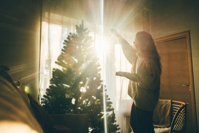 Rear view of woman looking through window