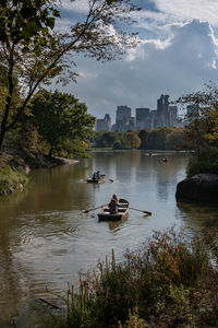 Boats in lake against sky in city