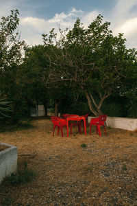 Empty chairs and table in park against sky