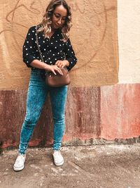 Full length of woman standing against wall