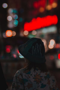 Rear view of girl standing in illuminated city at night