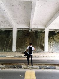 Rear view of man standing below bridge