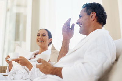 Happy couple in bathrobe enjoying tea at home