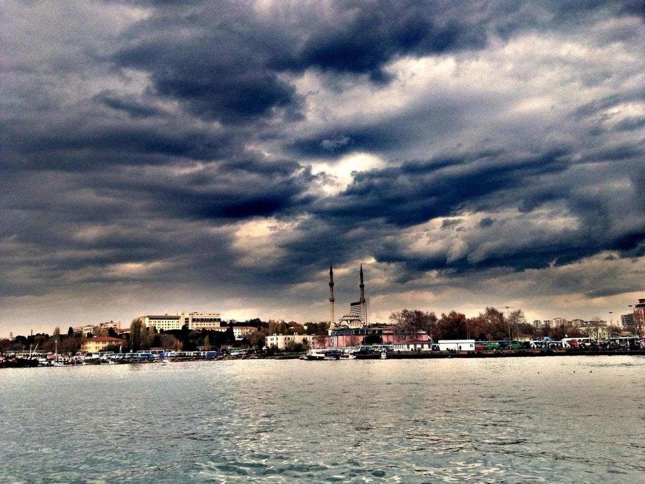 waterfront, building exterior, water, architecture, sky, built structure, cloud - sky, city, sea, cloudy, cityscape, river, cloud, residential district, crane - construction machinery, weather, storm cloud, dusk, commercial dock, rippled