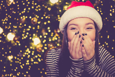 Close-up of smiling young woman against christmas tree