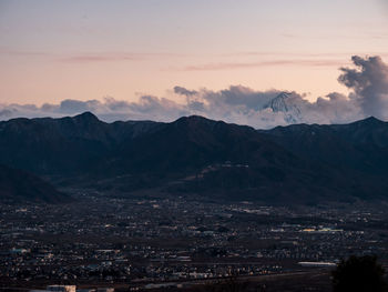 Aerial view of townscape and mountains against sky