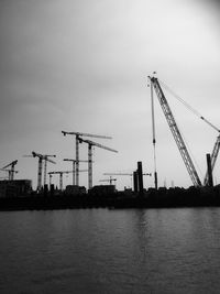 Cranes at commercial dock against sky