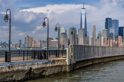 View of buildings by river against cloudy sky