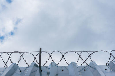 Low angle view of barbed wire against sky