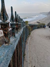 Row of railing at beach against sky