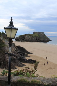 Street light on rock by sea against sky