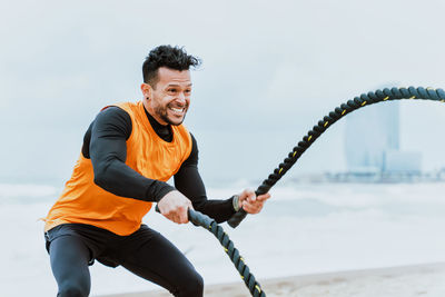 Male athlete exercising with rope at beach