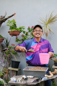 Smiling young man holding umbrella against plants