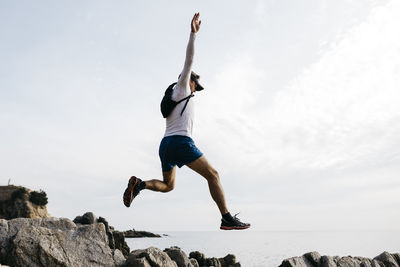 Low angle view of man jumping against sky