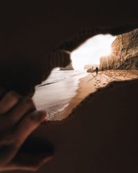 People at beach seen through torn cardboard