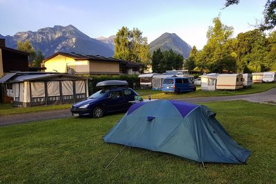 Tent by car on grass at campsite against sky