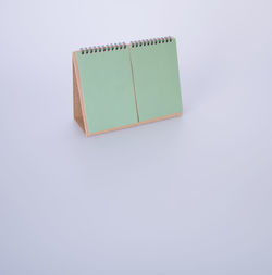 High angle view of blank green desk calendar against white background