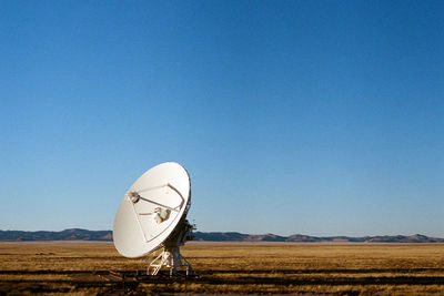 Windmill on landscape against clear blue sky