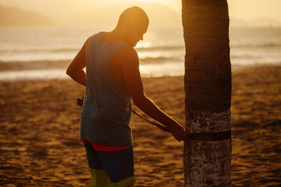 Man standing on beach against sky during sunset