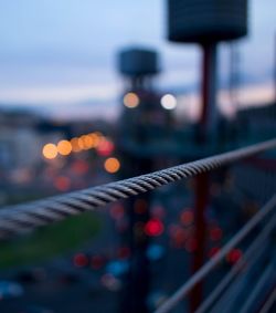 Close-up of cable against illuminated lights at dusk