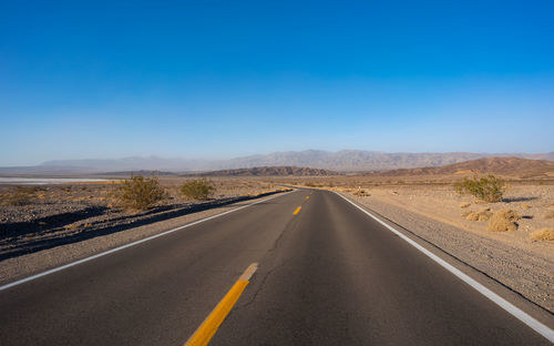 Road leading towards mountains against sky