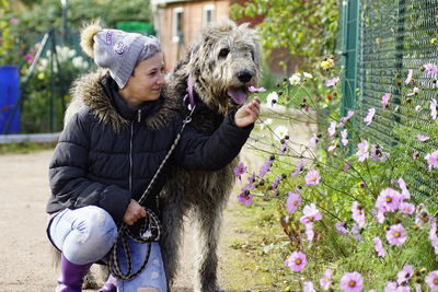 Mature woman with dog holding flower on footpath