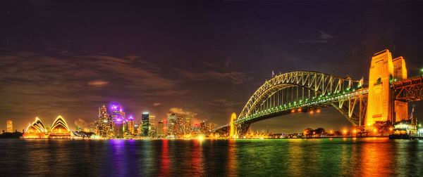 Illuminated bridge over river at night