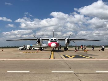 People at airport runway against sky