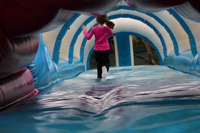 Rear view full length of girl playing in bouncy castle