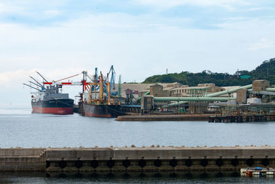 Cranes at harbor against sky
