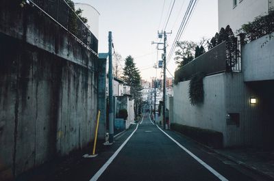 Empty road amidst buildings against sky at dusk