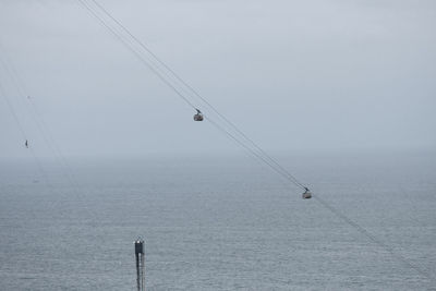 Ski lift over sea against clear sky