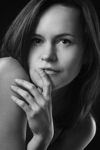 Close-up portrait of beautiful woman against black background