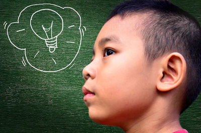 Side view of boy with drawing on blackboard