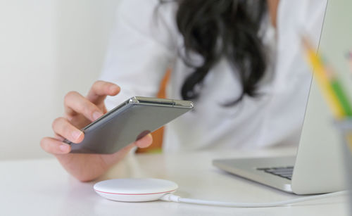 Midsection of man using mobile phone on table
