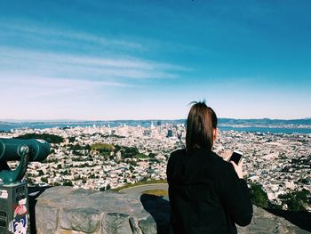 Rear view of woman looking at cityscape against sky