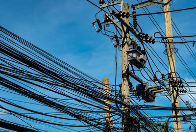 Low angle view of electricity pylon against blue sky