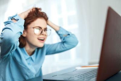 Rear view of woman using phone while sitting on table