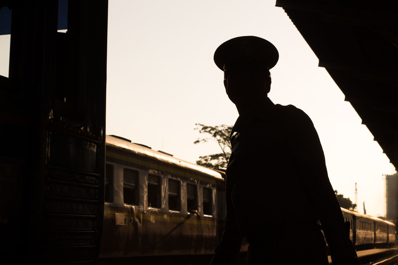 SILHOUETTE MAN STANDING BY TRAIN AGAINST CLEAR SKY