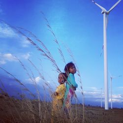 Cute kids standing by windmill against sky