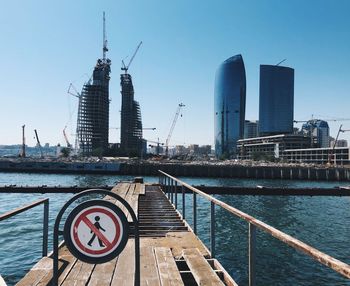 Modern buildings by river against sky in city