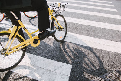 Low section of man with bicycle crossing on road